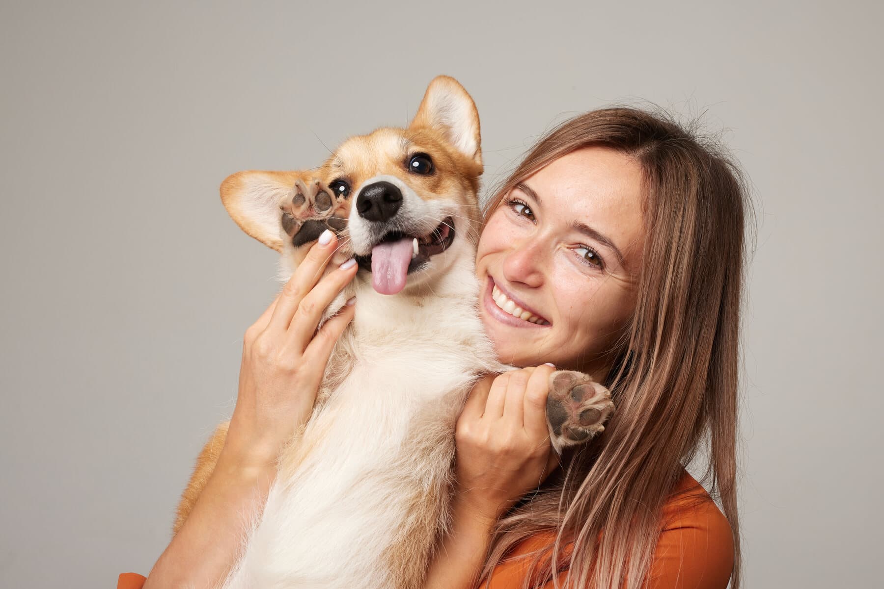 A smiling pet parent holding a corgi